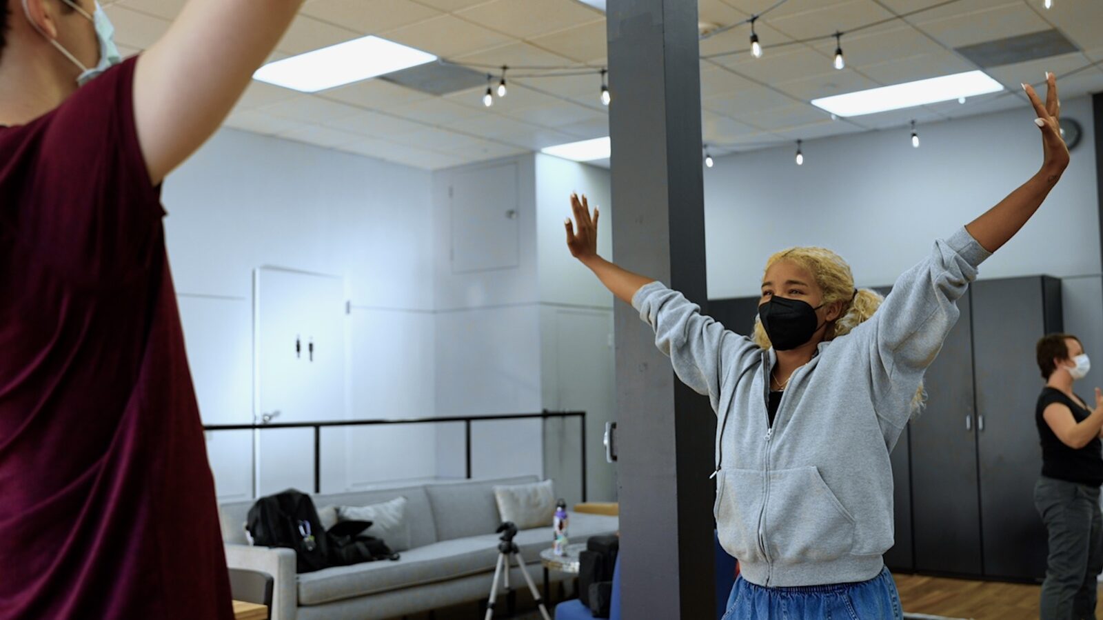 A participant with arms raised in a rehearsal room