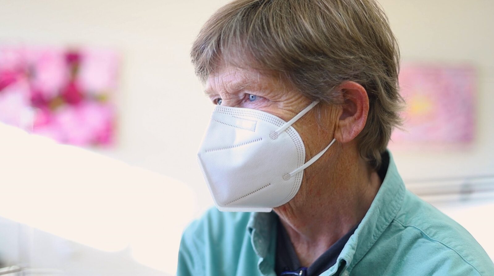 An elder participant in a mask, listening