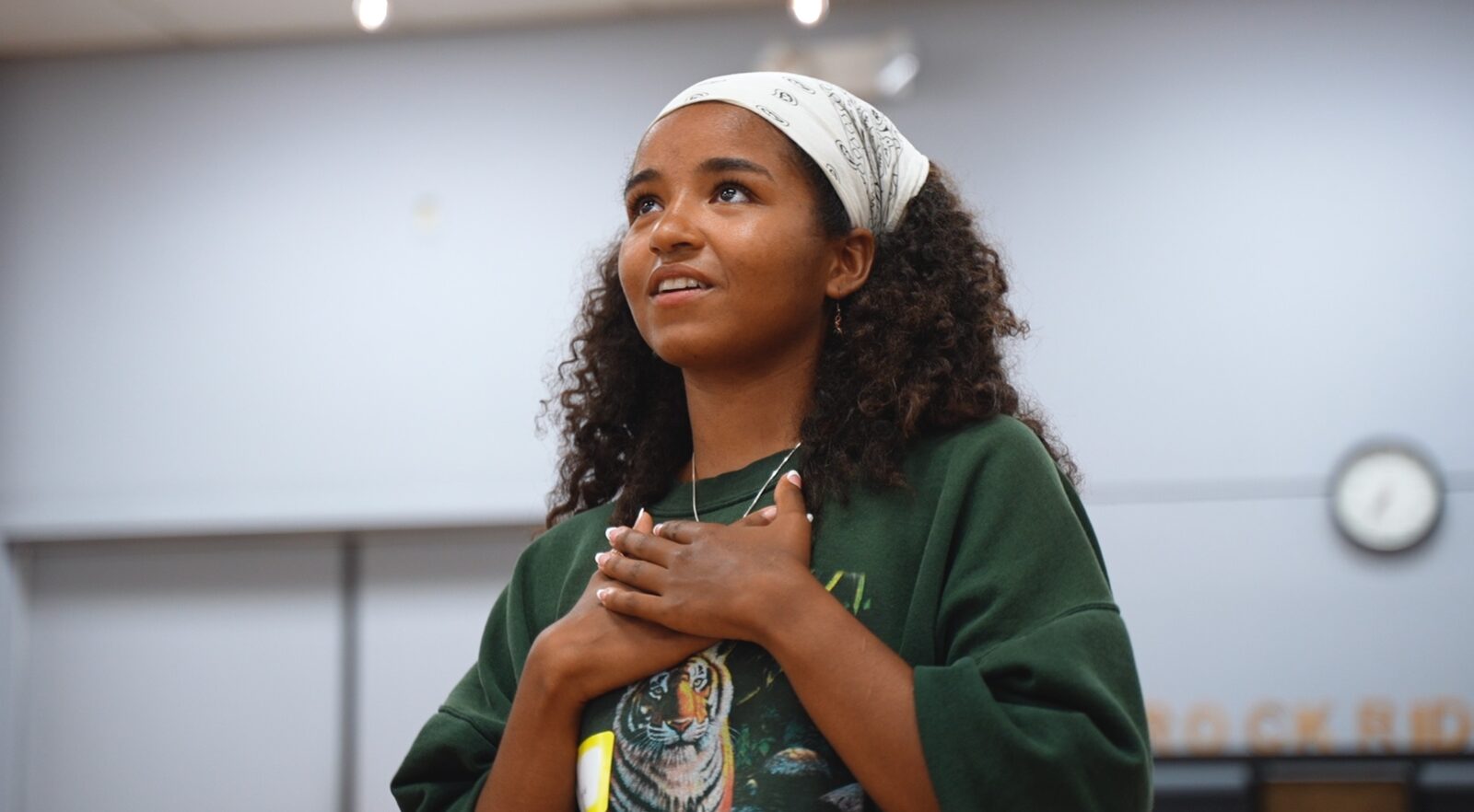 A young Black participant with hands over their chest, looking up