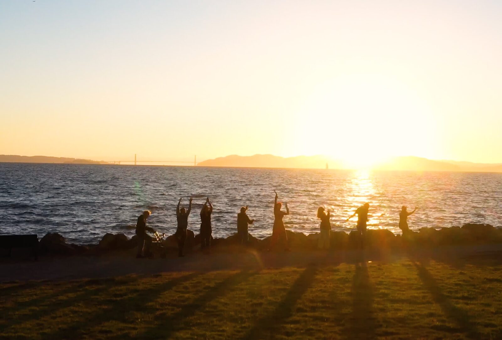 The group silhouetted with arms raised against the setting sun